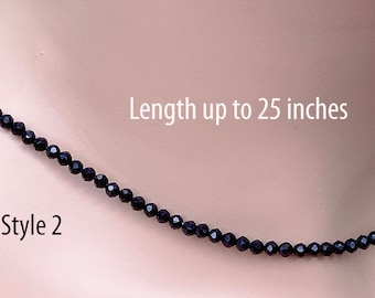 Op de afbeelding: Een zwarte kralenketting, Stijl 2, met een lengte tot 63,5 cm. De ketting bestaat uit kleine, donkere kralen, waardoor een eenvoudig maar elegant ontwerp ontstaat. De kralen zijn aan elkaar geregen tot een delicate ketting.