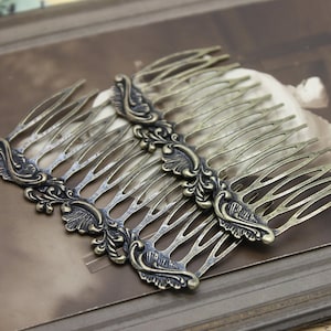 May include: Two antique gold hair combs with ornate floral designs. The combs are made of metal and have a distressed finish.