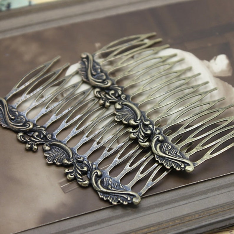 May include: Two antique gold hair combs with ornate floral designs. The combs are made of metal and have a distressed finish.