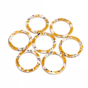 May include: Seven round, brown and white patterned plastic rings. The rings are all the same size and have a smooth, glossy finish.