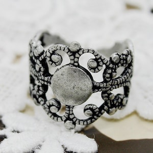May include: Silver filigree ring with a large, round, open center. The ring is made of a delicate, intricate design with a textured finish.