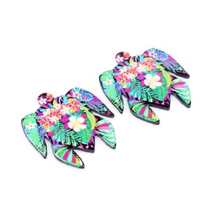 May include: Two black turtle-shaped earrings with a tropical floral print. The print features pink, purple, green, and white flowers and leaves.