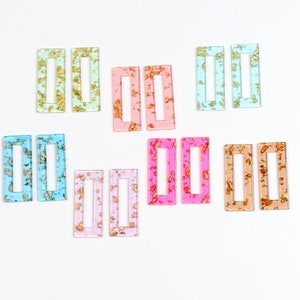 Può includere: Assortimento di otto paia di fermagli per capelli rettangolari in acrilico con glitter dorati. I fermagli sono in vari colori pastello, tra cui azzurro, rosa, verde chiaro e beige.
