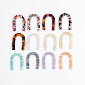 Peut inclure: Douze pièces en plastique en forme de U de différentes couleurs et motifs, y compris écaille de tortue, blanc et bleu. Chaque pièce a un trou au sommet.