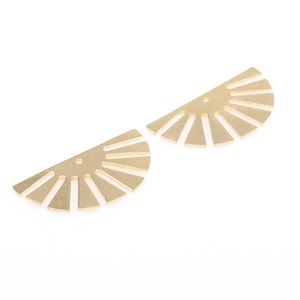 May include: Two gold metal sunburst shapes with a hole in the center. The shapes are half circles with rays emanating from the center.