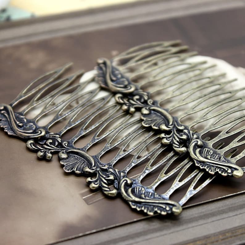 May include: Two antique gold hair combs with ornate floral designs. The combs are made of metal and have a delicate, intricate pattern.