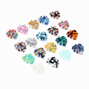 May include: Assortment of 18 colorful, patterned, plastic, tropical leaf shapes. The leaves are in various colors and patterns, including red, blue, green, yellow, orange, and brown.