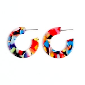 May include: A pair of colourful hoop earrings with a marbled pattern in shades of red, blue, yellow, and black.