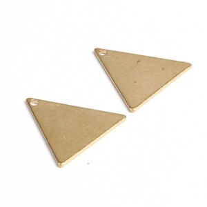 May include: Two gold-colored triangle-shaped metal charms with a small hole at the top.
