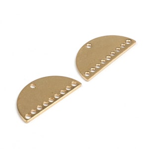 May include: Two gold-colored metal half-circle shapes with holes around the edge and two holes at the top.