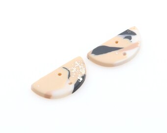 May include: Two half-circle shaped ceramic buttons with a beige background and black and white marbling. The buttons have gold flecks and two holes.