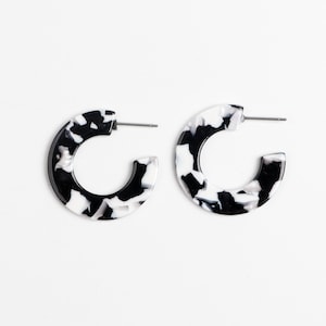 May include: A pair of black and white hoop earrings with a marbled pattern.