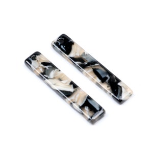 May include: Two black and white marbled rectangular pendant charms with a hole at the top for hanging.