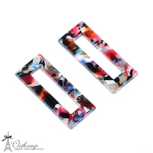以下が含まれることがあります： カラフルな抽象的なパターンが施された長方形のヘアクリップ2個。クリップはプラスチック製で、透明で光沢のある仕上げになっています。