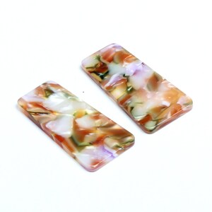 May include: Two rectangular hair clips with a marbled pattern in shades of white, brown, green, and purple.