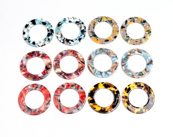 May include: Twelve round, colorful, patterned, plastic rings with a hole in the center. The rings are in various colors, including red, blue, yellow, and brown.