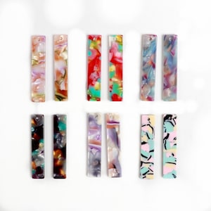 Könnte beinhalten: Set mit 12 bunten rechteckigen Acryl-Ohrringen mit verschiedenen abstrakten Mustern. Die Ohrringe sind in den Farben Rosa, Blau, Grün, Rot und Weiß.