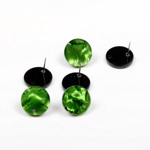 May include: Four pairs of green and black stud earrings. The earrings have a round, marbled green design with a black backing.