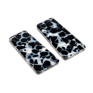 May include: Two black and white rectangular acrylic charms with a marbled pattern.