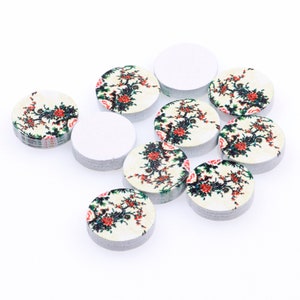 May include: Assortment of round wooden craft embellishments with a white background and floral designs in red, green, and black.