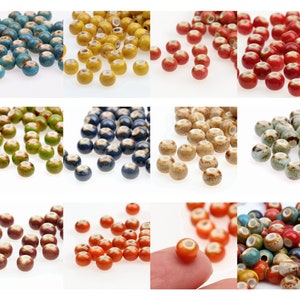 May include: A selection of ceramic beads in diverse colours, such as blue, yellow, red, green, and brown. Each bead features a speckled or glazed finish and a hole for threading. Suitable for jewellery making and crafts.
