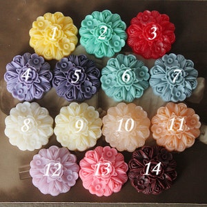 May include: Fourteen round, decorative, floral-shaped soaps in various colors, including yellow, green, red, purple, blue, white, pink, and brown. Each soap is numbered 1 through 14.