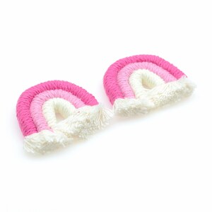 May include: Two pink and white crocheted rainbows with white fringe.