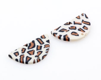 May include: Two white half-circle shaped plastic buttons with a brown and black leopard print design.