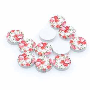 May include: A collection of ten round wooden craft embellishments with a white background and a red floral pattern.
