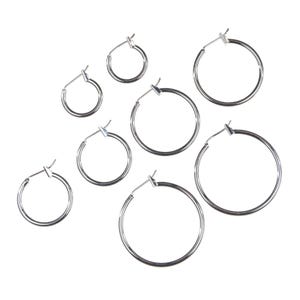 Puede incluir: Un conjunto de pendientes de aro plateados de varios tamaños sobre un fondo blanco. Los pendientes tienen un diseño sencillo y clásico con cierre de bisagra. Los aros varían de pequeños a grandes, ofreciendo diversas opciones de estilo.