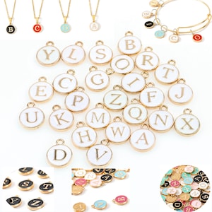 May include: Assortment of gold-tone alphabet letter charms with white enamel. The charms are in various shapes and sizes, with some having a gold-tone finish and others having a white enamel finish. The charms are arranged in a random pattern on a white background.