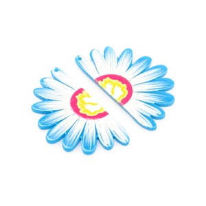 May include: Two blue plastic flower charms with white petals and a pink and yellow center. The charms are split in half and can be used for jewelry making.