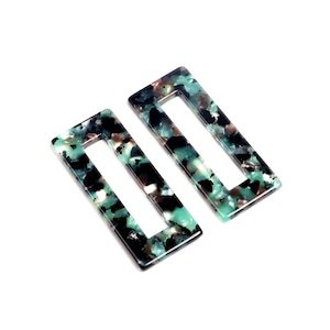 Peut inclure: Deux pinces à cheveux rectangulaires avec un motif marbré vert, noir et marron.