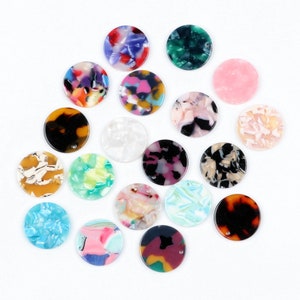 May include: Assortment of 15 round, colourful, patterned resin cabochons. Each cabochon has a unique design with swirls and marbling. The cabochons are approximately 2.5 cm in diameter.