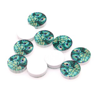 May include: Assortment of round wooden craft embellishments with a peacock feather design. The embellishments are green, blue, and gold with a white background.