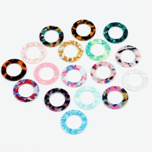 Peut inclure: Assortiment de 16 anneaux décoratifs ronds, en plastique, à motifs colorés. Les anneaux mesurent environ 2,5 cm de diamètre et ont un trou au centre.