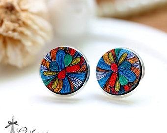 May include: A pair of colorful earrings with a silver backing. The earrings feature a circular design with a blue, red, yellow, green, and white pattern.