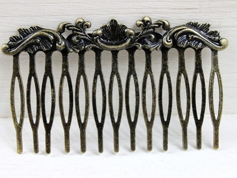 May include: A gold-toned metal hair comb with a decorative floral design. The comb has 12 teeth.
