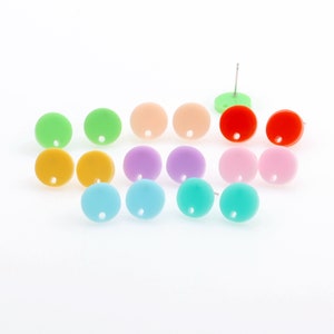May include: A set of 12 colourful round earrings. The earrings are made of acrylic and come in a variety of colours, including red, orange, yellow, green, blue, purple, and pink.