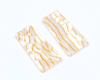 May include: Two white rectangular acrylic hair clips with a gold marbled pattern.