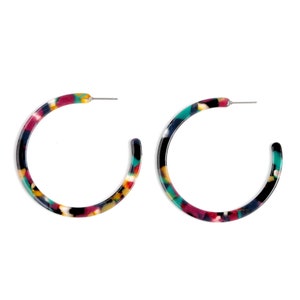 May include: A pair of colorful hoop earrings with a black, white, red, yellow, and teal marbled pattern.