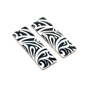 Puede incluir: Dos pendientes rectangulares negros y blancos con un patrón tribal.