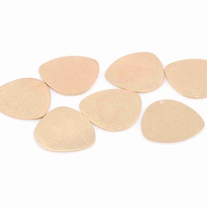 May include: Eight gold-toned triangle-shaped metal charms with a hole at the top. The charms have a slightly textured surface.