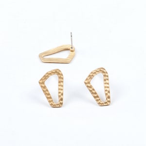 Op de afbeelding: Een paar gouden geometrische oorbellen met een gehamerde textuur. De oorbellen zijn gevormd als een onregelmatig vijfhoek met een uitsparing in het midden.