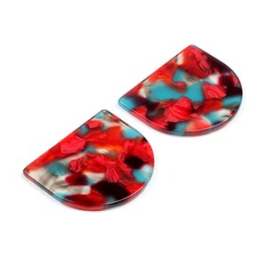 Puede incluir: Dos piezas de plástico marmoleado rojo, azul y negro en forma de semicírculo. Las piezas son translúcidas y tienen un aspecto moteado.