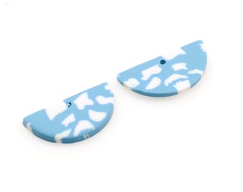 May include: Two blue and white half-circle shaped polymer clay earrings with a hole in the center.
