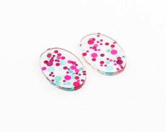 May include: Two oval-shaped resin earrings with a clear background and pink and blue glitter embedded inside.