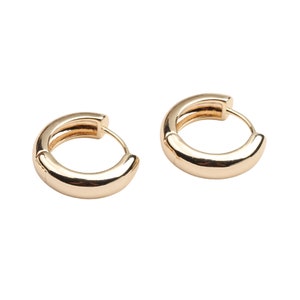 May include: A pair of gold hoop earrings. The earrings are simple and classic, with a smooth, polished finish.