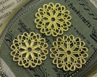 May include: Three gold metal filigree embellishments with a circular design. The embellishments are on a green fabric background.
