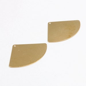 May include: Two gold-colored metal half-circle shapes with a small hole at the top.